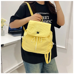 Close-up of bright yellow nylon drawstring backpack showing crinkle texture and flap