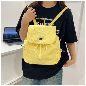 Lifestyle view of a yellow drawstring nylon backpack with a minimalist front brand tag