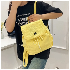 Detail of yellow drawstring backpack with crinkle texture and animal logo on flap