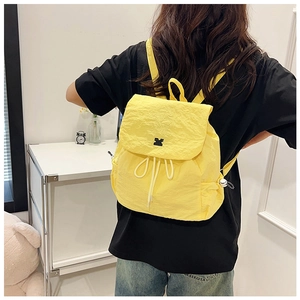 Detail of yellow nylon drawstring backpack showing micro-wrinkle texture and cat embroidery