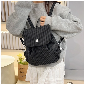 Detail of minimalist black and white plaid backpack with metal clasp and drawstring