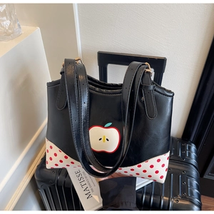 Detail of vintage black apple pattern tote bag with polka dot accents on a suitcase
