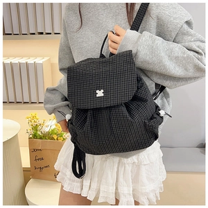 Detail of checkered drawstring backpack featuring a cute bear-shaped metal buckle and canvas