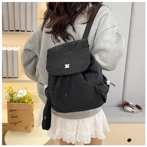 Detailed view of black and white checkered backpack fabric with geometric buckle on cover