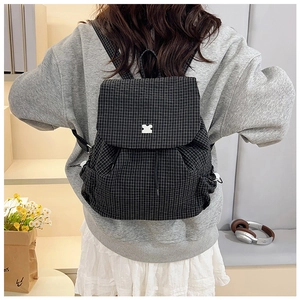 Detail of checkered canvas backpack with drawstring closure and puzzle piece ornament