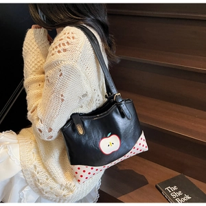 Detailed close-up of retro polka dot panel on vintage black shoulder bag with apple motif