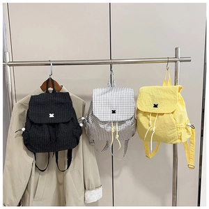 Detailed view of mini drawstring backpacks in plaid and yellow with bow accents