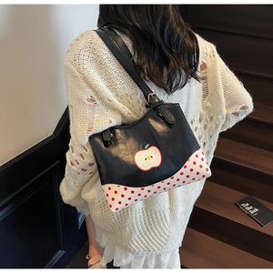 Detail of cute apple print shoulder bag with red polka dot canvas on wooden stairs