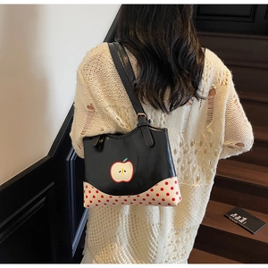 Detail showing a girl wearing a black leather apple tote bag with polka dot pattern