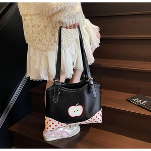 Detail of black leather tote bag with apple patch and red polka dot contrast corners