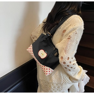 Detailed view of apple pattern and polka dot design on black leather tote bag