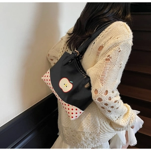 Detail of cute black shoulder bag with apple patch and red polka dot pattern on the side