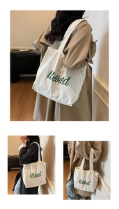 Detail view of cream canvas tote bag featuring green letters and adjustable drawstring closure