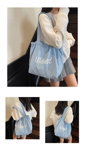 Detail of light blue canvas tote bag with drawstring closure and white script lettering