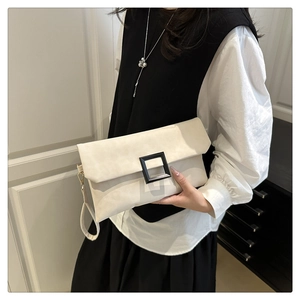 Detail of white envelope clutch bag with black square buckle and wristlet strap