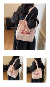 Close-up of pink drawstring tote bag with embroidered red Udbild cursive lettering