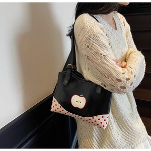 Side view of a vintage apple pattern tote bag worn by a model in a minimalist setting