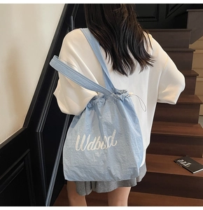 Close-up of light blue drawstring tote bag with white embroidery on nylon fabric