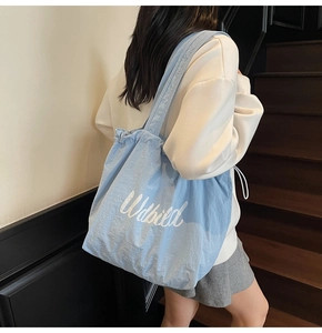 Close-up of light blue drawstring tote bag with white cursive Udbild printing