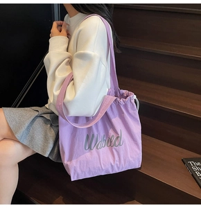 Close-up of purple drawstring bucket bag with Wdbied print on canvas material