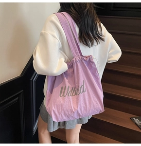 Shoulder shot of a purple drawstring tote bag with artistic font on high-quality fabric