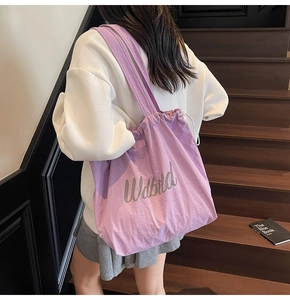 Detail of purple drawstring tote bag with aesthetic text on nylon textured fabric