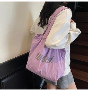 Detail of purple drawstring tote bag with Wabled print and lightweight nylon texture