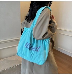 Detail of light blue tote bag with purple Udbild lettering and functional drawstring