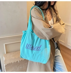 Close-up of bright sky blue canvas tote bag with purple Wdbild logo lettering detail