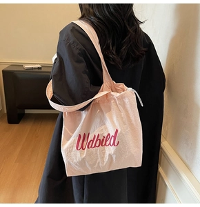 Macro shot of pink nylon drawstring bucket bag with red Wdbild script and textured fabric