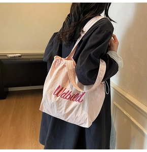 Close-up of pink fabric tote bag featuring drawstring closure and Udbild logo detail