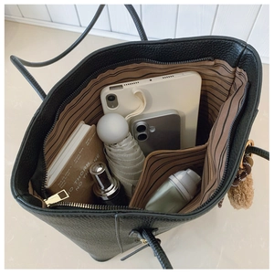Top view of spacious interior of black tote bag with striped lining and daily essentials