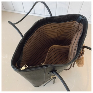 Detail view of the striped fabric lining and inner zipper pocket of the black tote bag
