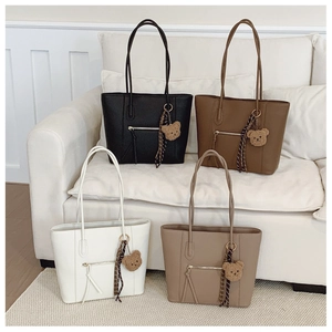 Detail of four colorful faux leather tote bags with cute bear charms and silk scarves