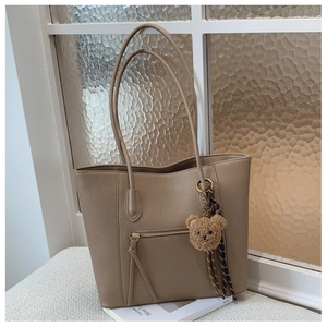 Detail of beige tote bag with litchi texture and metal zipper pocket
