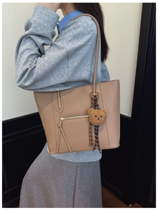 Detail of khaki pebbled leather tote bag with tassel zipper and plush bear charm
