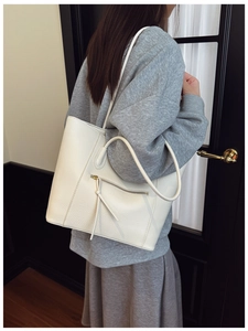 Close-up of beige lychee grain leather tote bag featuring a front zipper pocket detail
