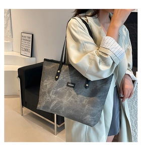 Dettaglio della borsa tote grigia marmorizzata con etichetta fashion e spalline lunghe
