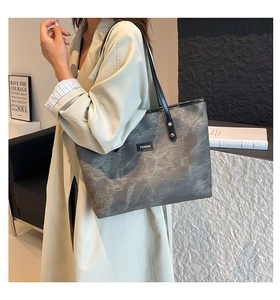 Grande borsa shopper grigia con trama marmorizzata indossata sopra un trench beige