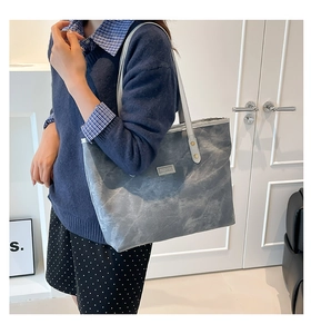 Detail of grey marbled tote bag featuring silver Fashion plaque and metal rivet hardware