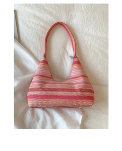 Detailed close-up of colorful striped woven shoulder bag with hobo silhouette on fabric
