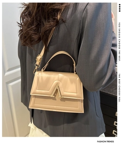 Detailed view of beige crossbody bag with gold A-shaped buckle and geometric stitching