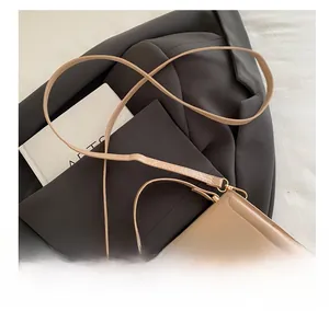 Detail of beige leather bag with golden V-shaped buckle on a grey suit background