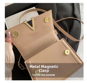 Detail of the light apricot crossbody bag with a gold V-shaped magnetic snap closure
