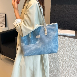 Minimalist light blue tote bag with long white strap worn by a model in a modern interior