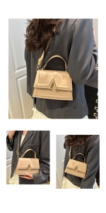 Close-up of beige crossbody bag with V-shaped gold clasp and adjustable strap