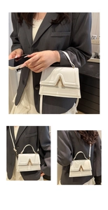 Detailed view of a white vintage handbag with a gold V buckle and adjustable strap