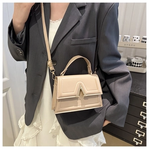Close-up of beige crossbody bag with quilted PU leather and gold V-shaped metal buckle
