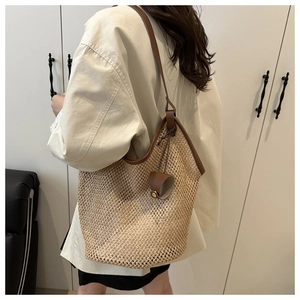 Detail of hand-woven straw tote with leather straps on a cream blazer model outfit