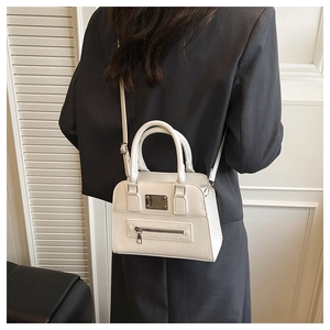 Detail of white PU leather handbag featuring decorative zippers and adjustable strap